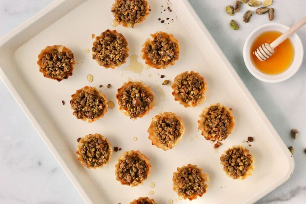 Pistachio Baklava bites on baking sheet drizzle with honey