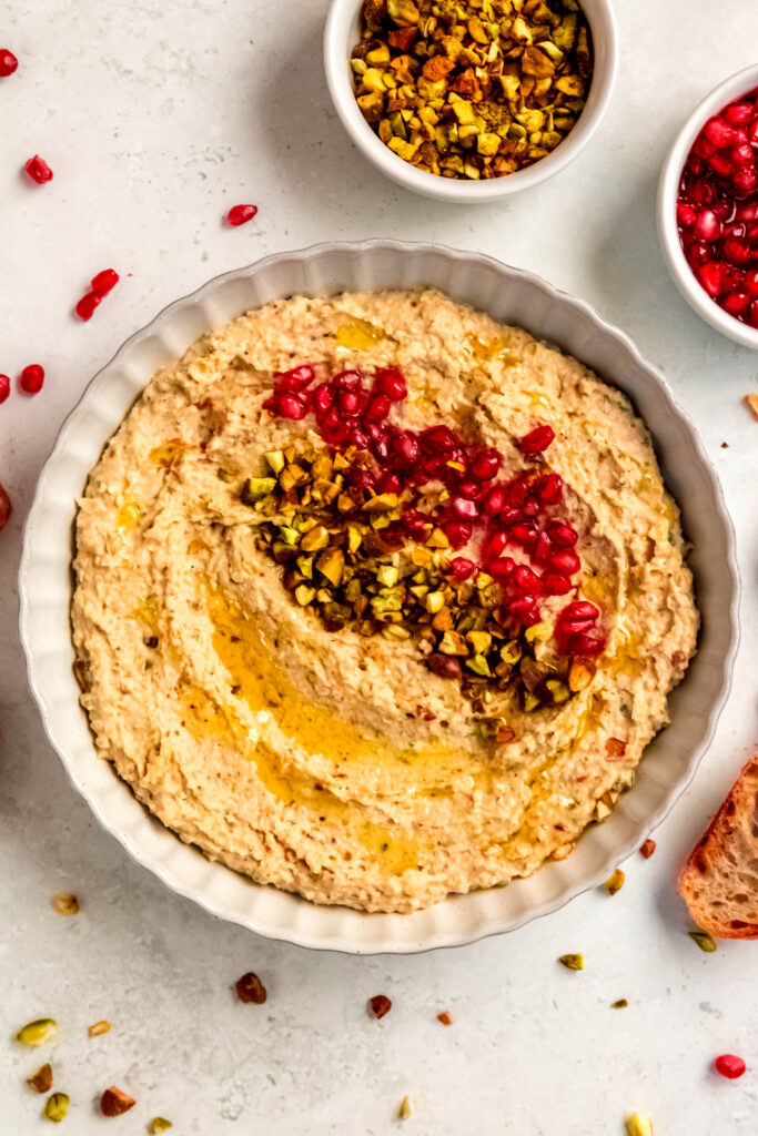 White bean crostini spread topped with pistachios and pomegranate seeds.