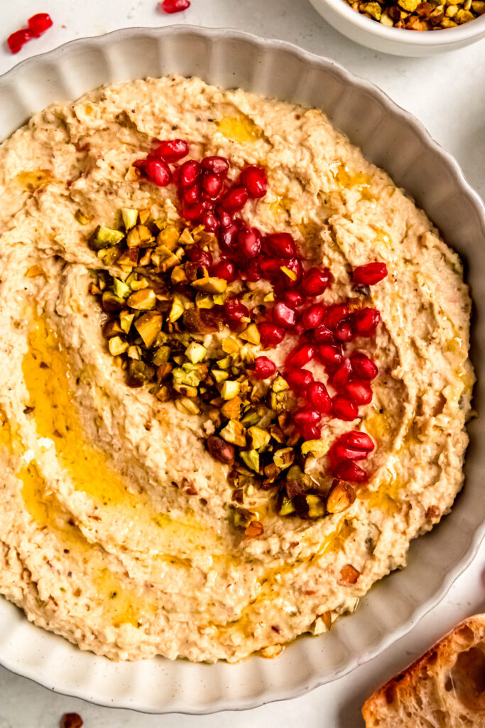 White bean crostini spread topped with pistachios and pomegranate seeds.