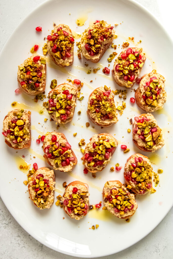 Pistachio and white bean crostinis on white platter 