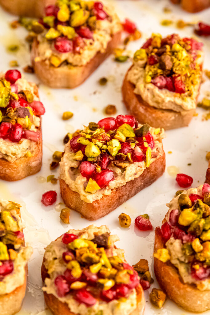 Pistachio and white bean crostinis topped with pomegranate seeds.