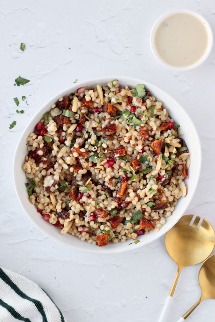 Couscous salad with dressing and serving spoon