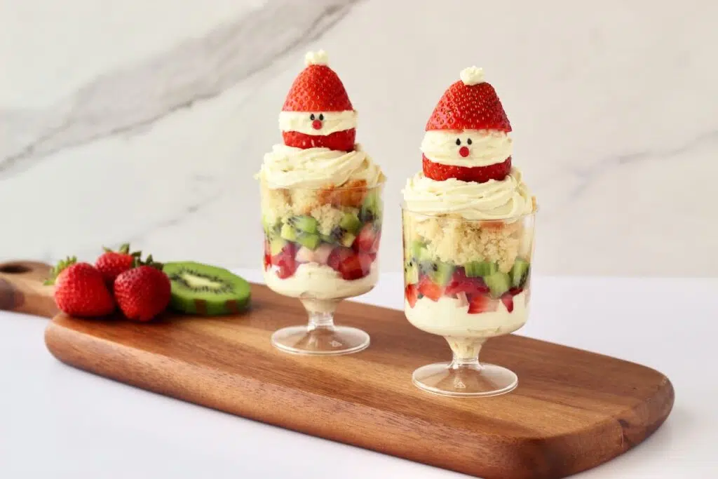 Individual Christmas Trifles on wood board with fresh strawberries and kiwi