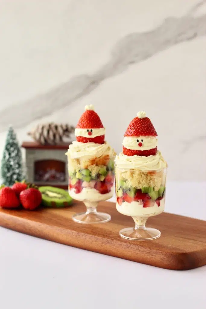 Individual Christmas Trifles on wood board with festive decor in background.