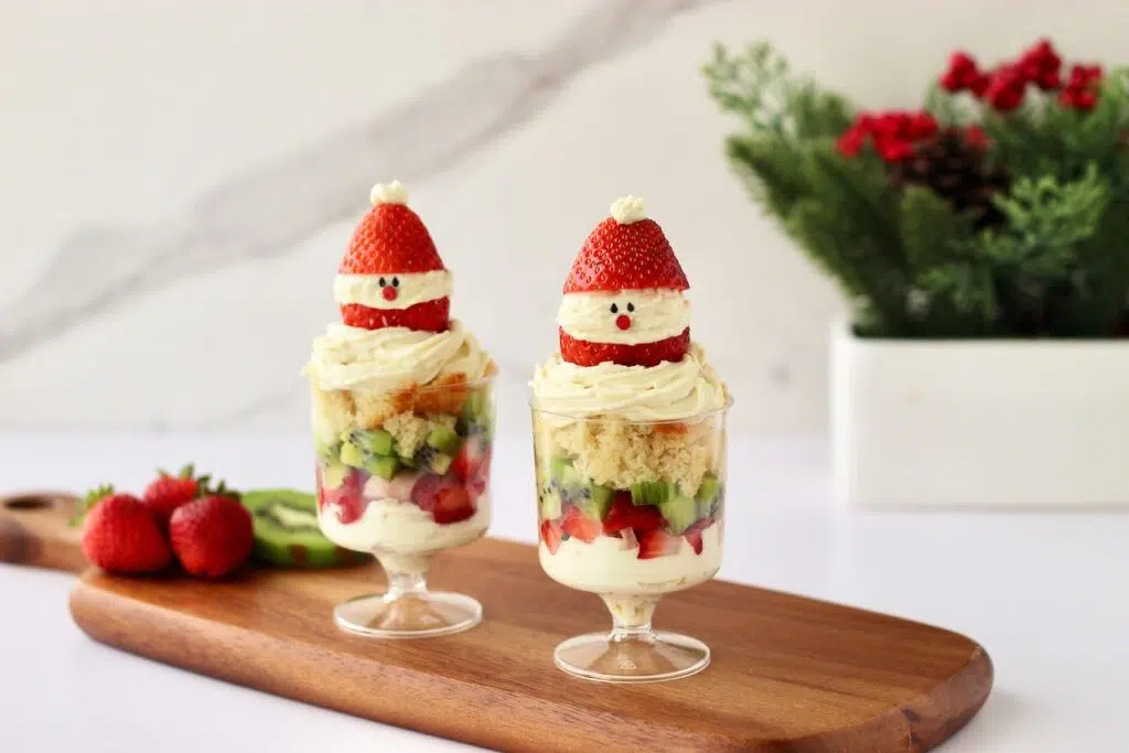 Individual Christmas Trifles on wood board with fresh strawberries and kiwi