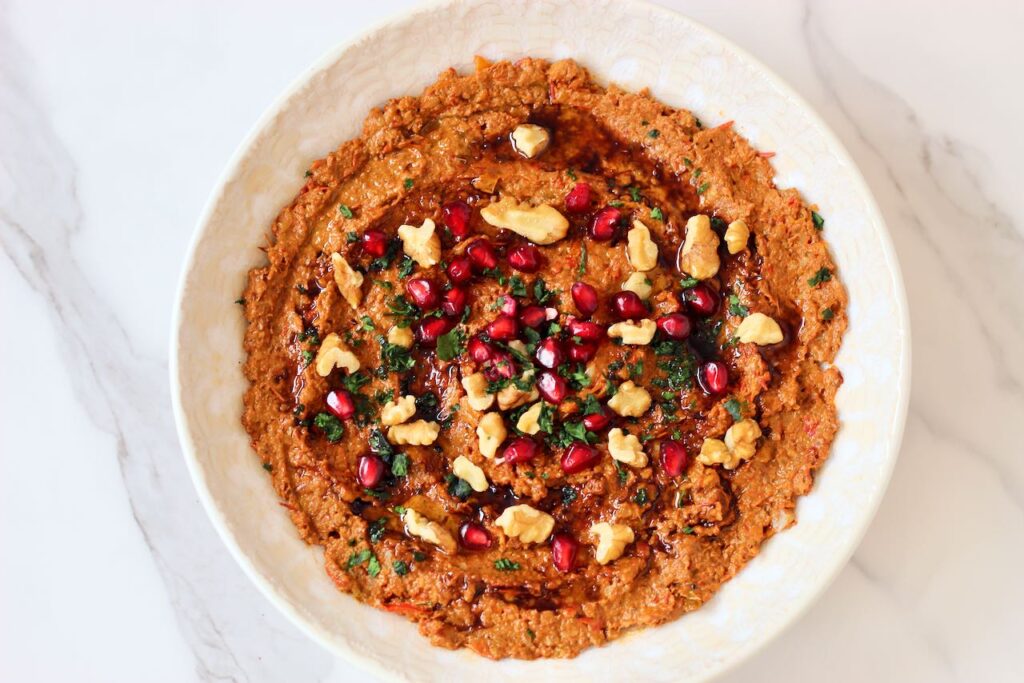 Muhammara with pomegranate seeds, walnuts, and cilantro.