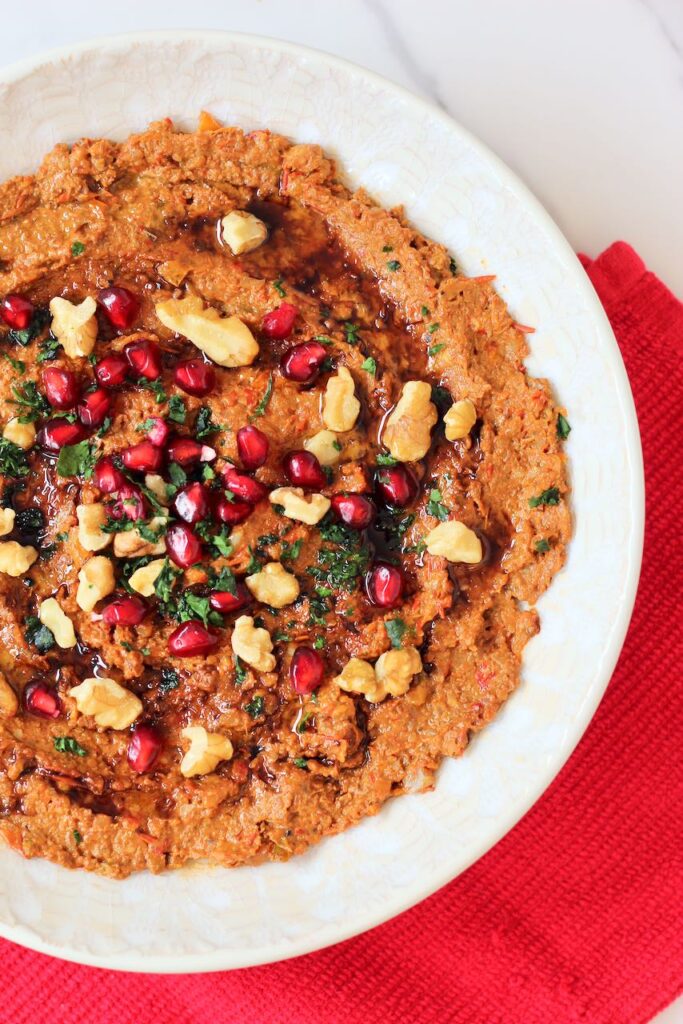 Muhammara with pomegranate seeds, walnuts, and cilantro.