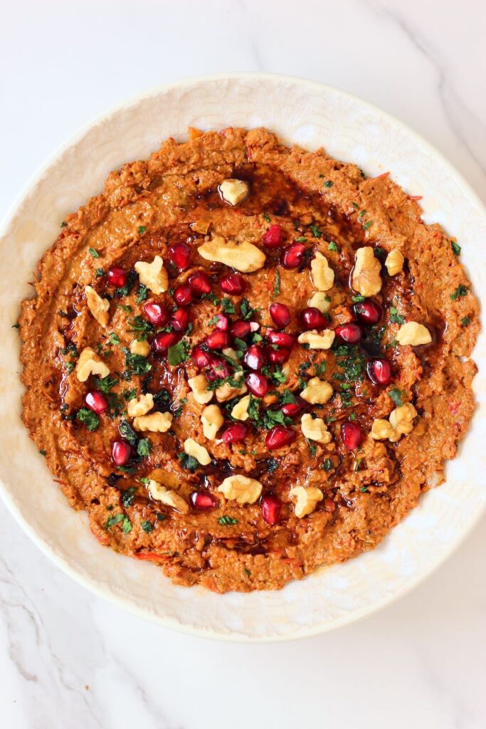 Muhammara with pomegranate seeds, walnuts, and cilantro.