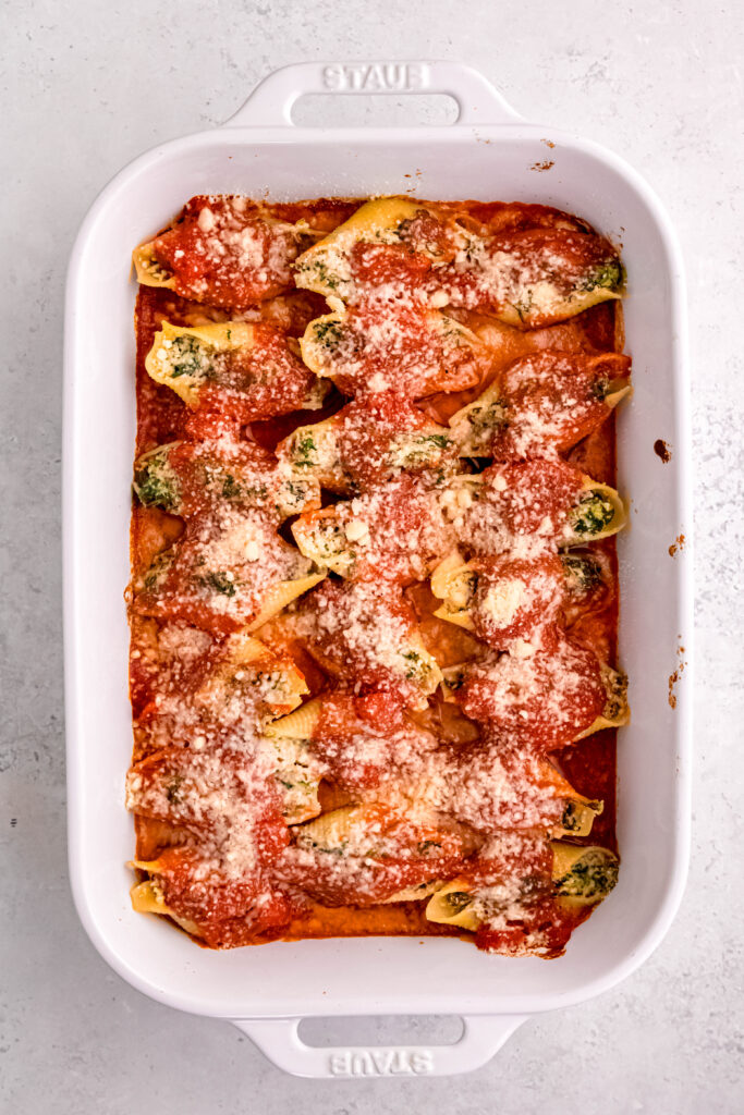 Stuffed shells in baking dish with parmesan cheese sprinkled on