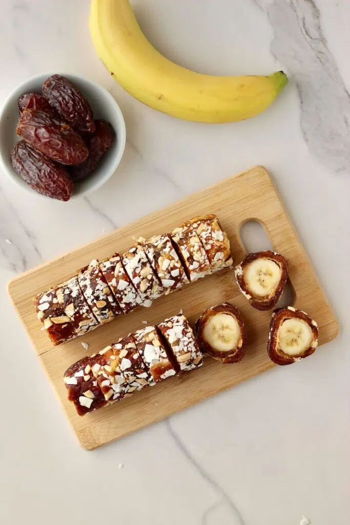 Banana sushi on a cutting board with Medjool dates and banana next to it