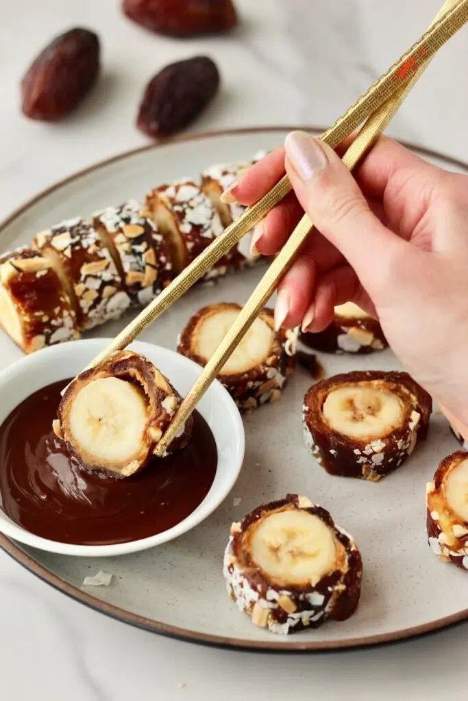 Dipping the banana sushi into the melted chocolate