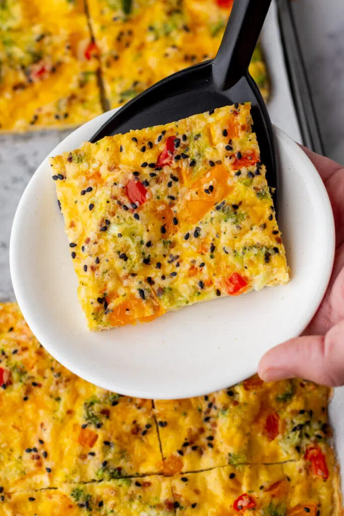 Spatula putting sheet pan eggs on white plate