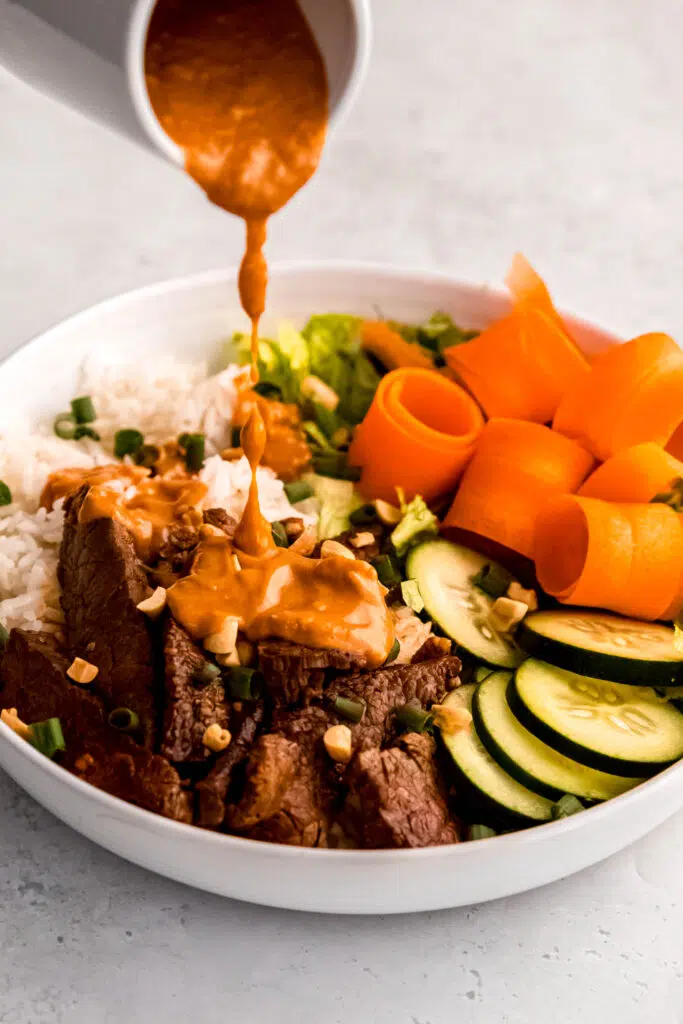 Bulgogi-Inspired Bowl with Gochujang Peanut Sauce Pouring On To Steak