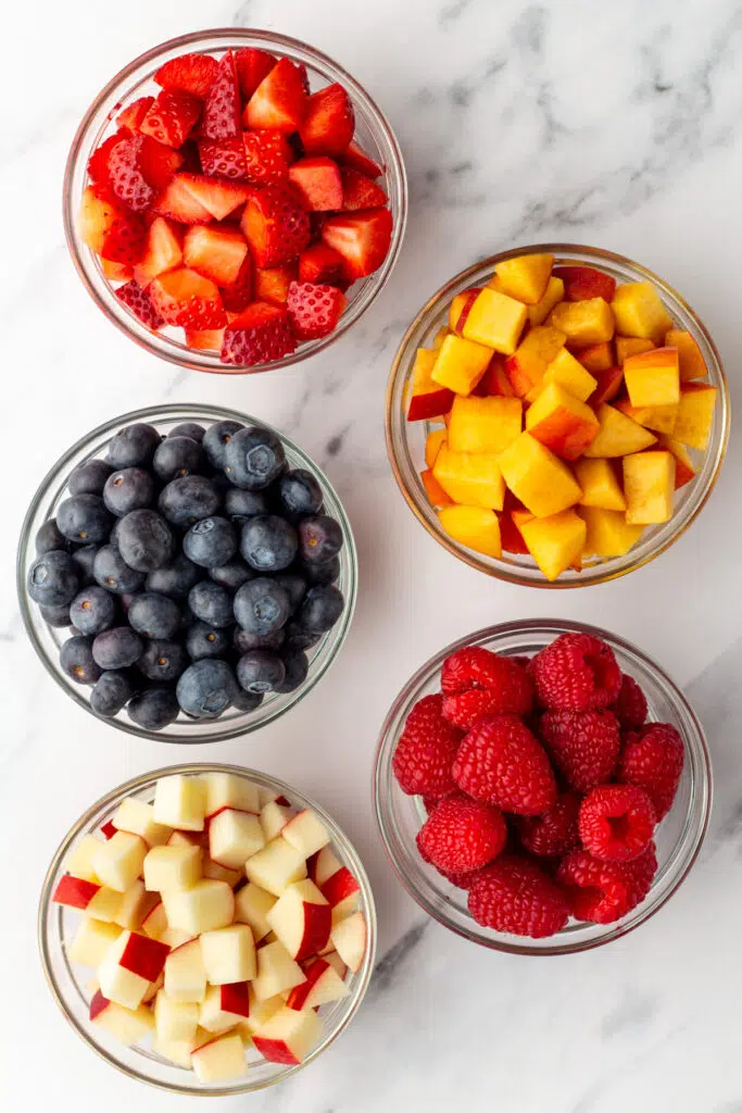 Fruit of your choice cut up in bowls: strawberries, nectarines, blueberries, raspberries, and apples