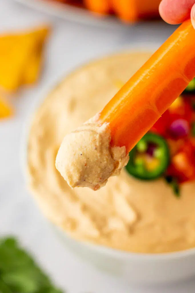 Carrot stick dipped in cottage cheese queso dip