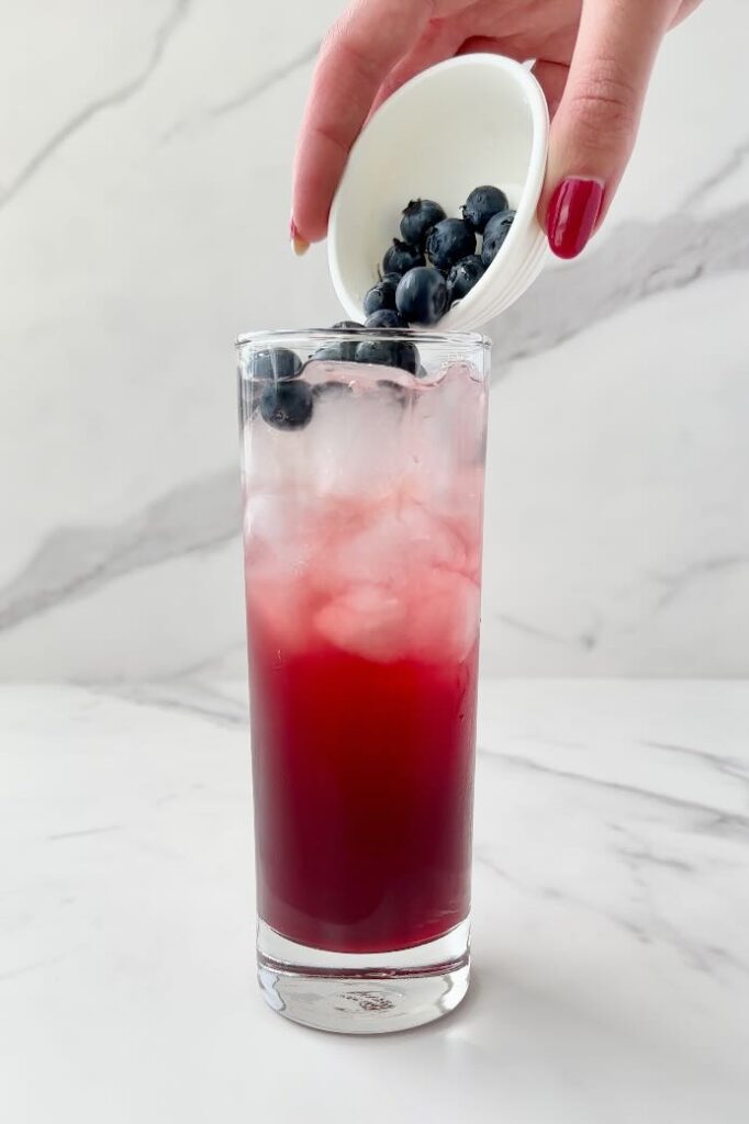 Pouring blueberries on top of drink