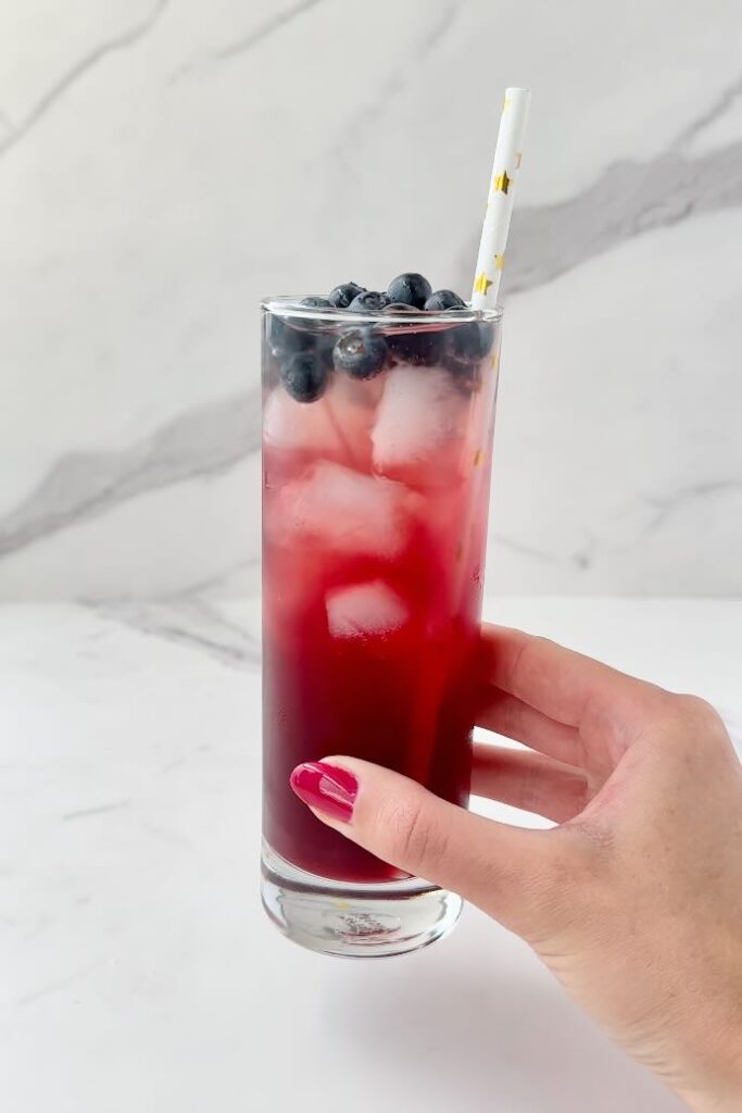 Hand holding diy electrolyte drink with straw