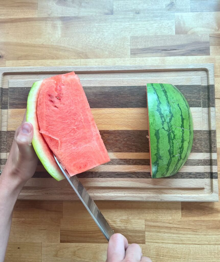 Knife cutting between the rind and flesh of watermelon