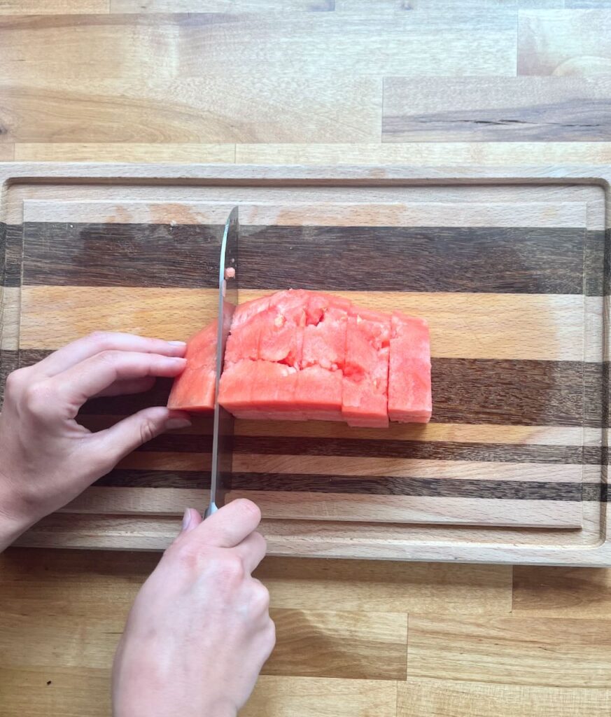 Rindless watermelon being cut lengthwise even stips