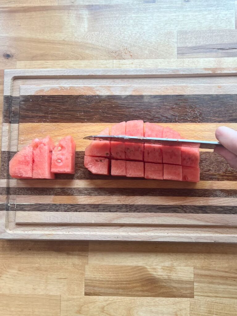 Watermelon being cut crosswise from lengthwise cuts