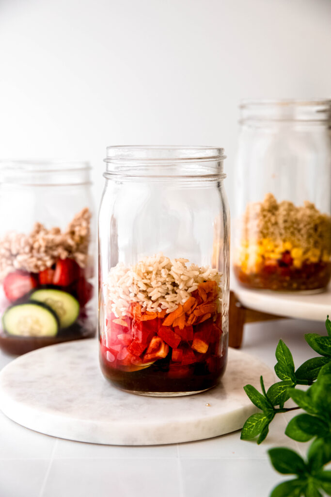 Mason jar with grains on top of veggies and dressing