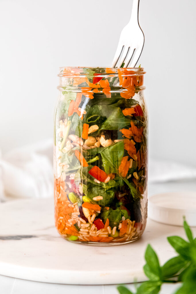 Mason jar with fork taking bite out of salad
