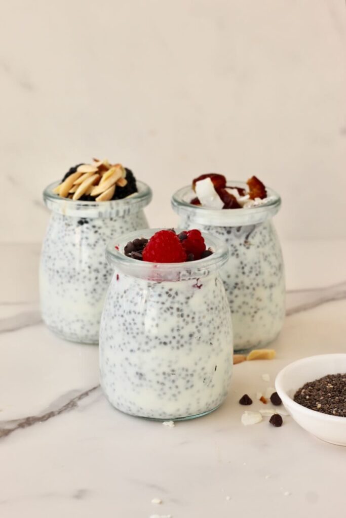 3 types of chia pudding in jars with different toppings and chia seeds in bowl