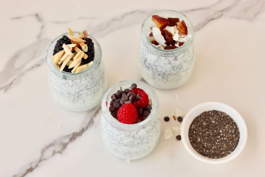3 types of chia pudding in jars and chia seeds in bowl