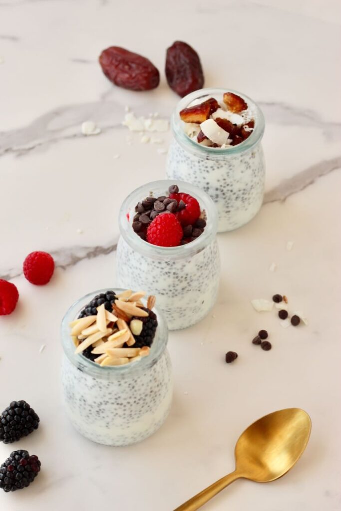 3 types of chia pudding in jars with different toppings and gold spoon