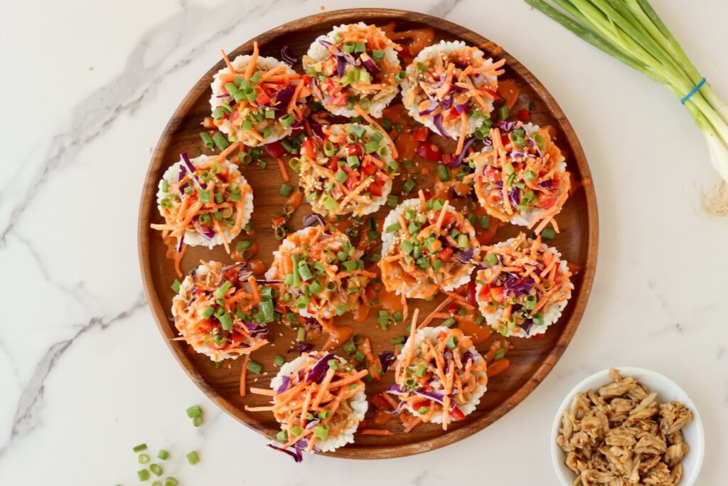 Korean BBQ Chicken Rice Cups on wood serving plate with green onion and chicken in background