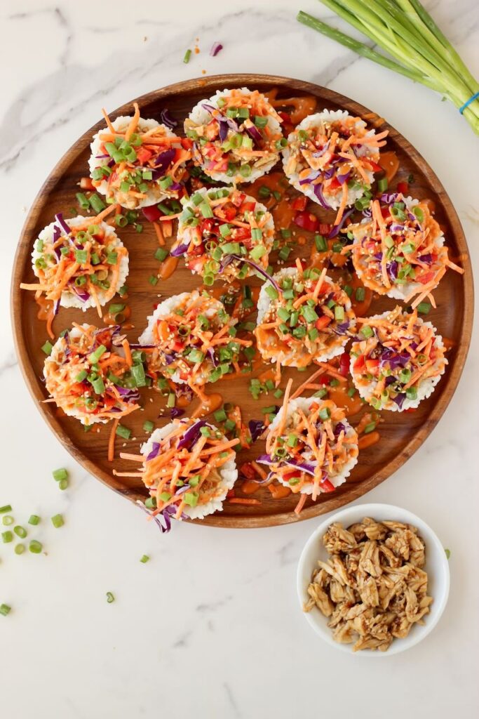 Korean BBQ Chicken Rice Cups on wood serving plate with bowl of chicken on side