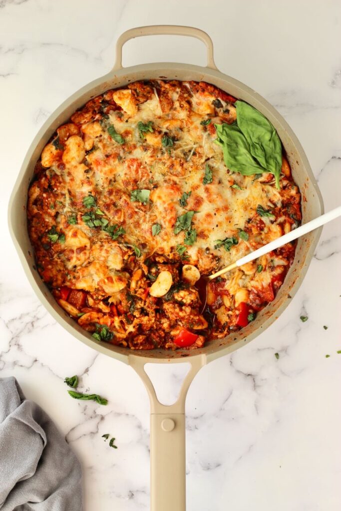 Pizza beans in skillet with spoon and fresh basil