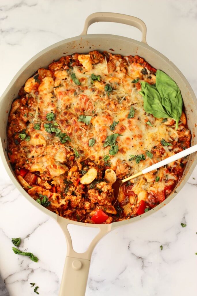 Pizza beans in skillet with spoon and fresh basil