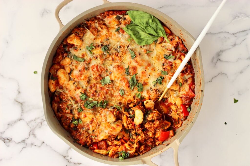 Pizza beans in skillet with spoon and fresh basil