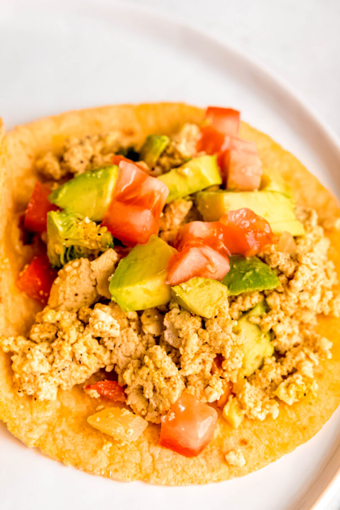 Tofu scramble in corn tortilla topped with avocado and tomatoes