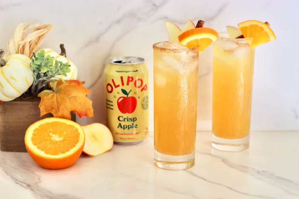 Two apple cider mocktails with olipop can and fresh orange 