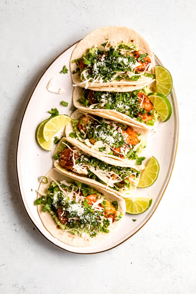 Assembled shrimp tacos on white plate