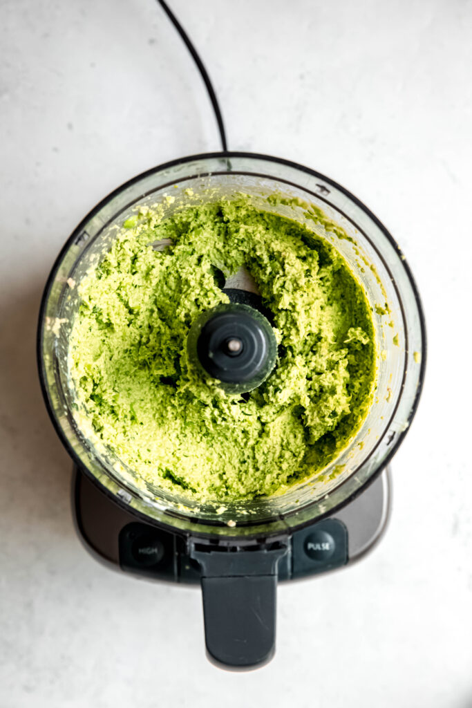 A food processor with green dip in it