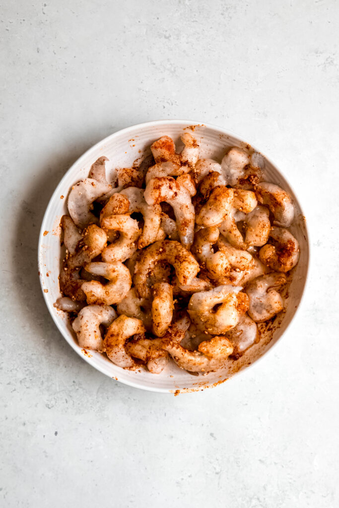 Raw shrimp with seasonings in white bowl