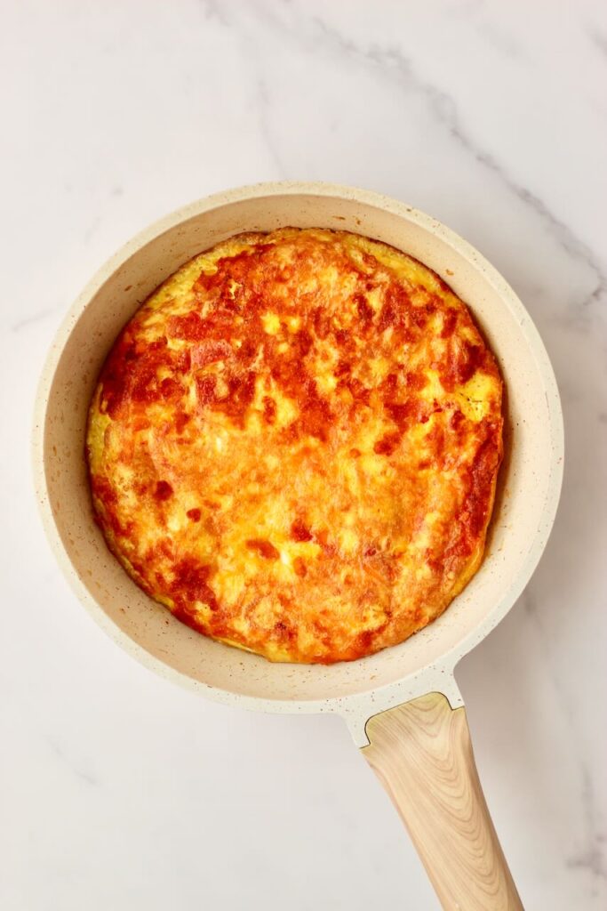 Egg pizza in skillet with wood handle