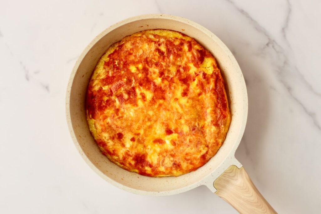 Egg pizza golden brown in skillet with white background