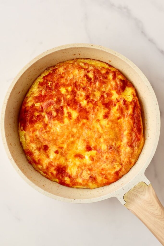 Egg pizza in skillet with wood handle
