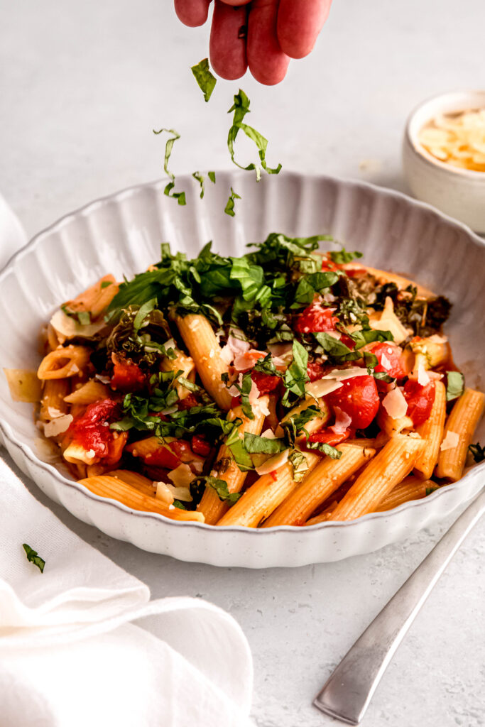 Sprinkling basil over bowl of pasta