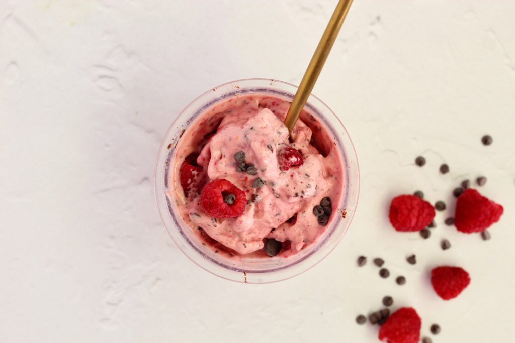 Raspberry Dark Chocolate Lifeway Kefir Protein Ice Cream in pint with gold spoon and raspberries in background