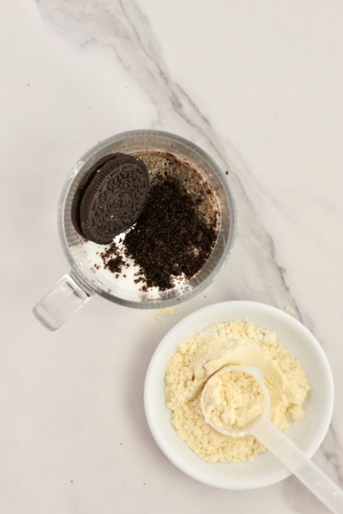 Oreo protein mug cake topped with oreo and protein powder in background