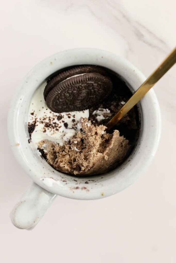 Gold spoon in oreo protein mug cake topped with oreo and yogurt