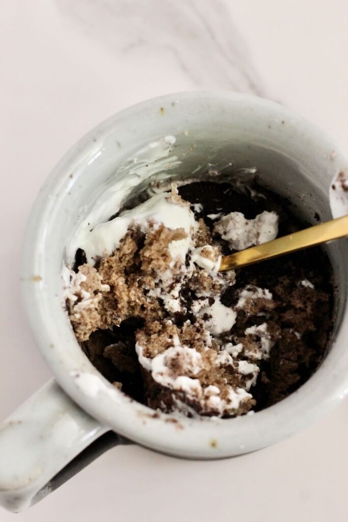 Oreo protein mug cake with gold spoon mixing it up