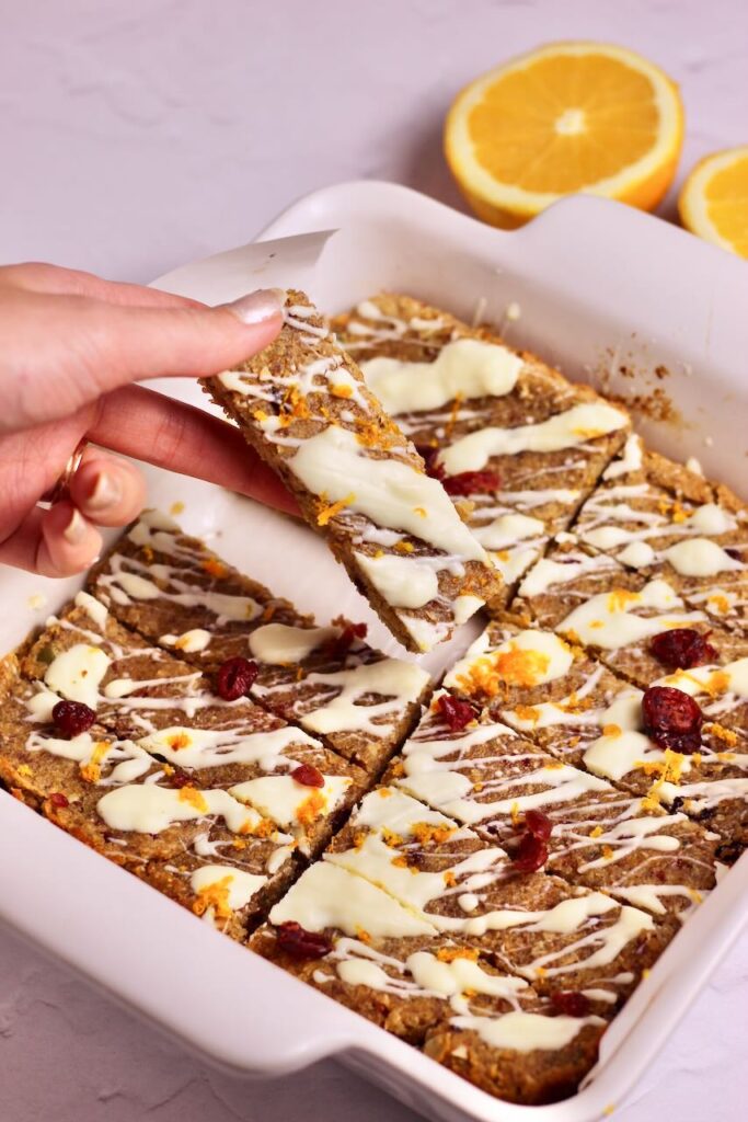 Hand taking Cranberry Orange Energy Bars from white dish