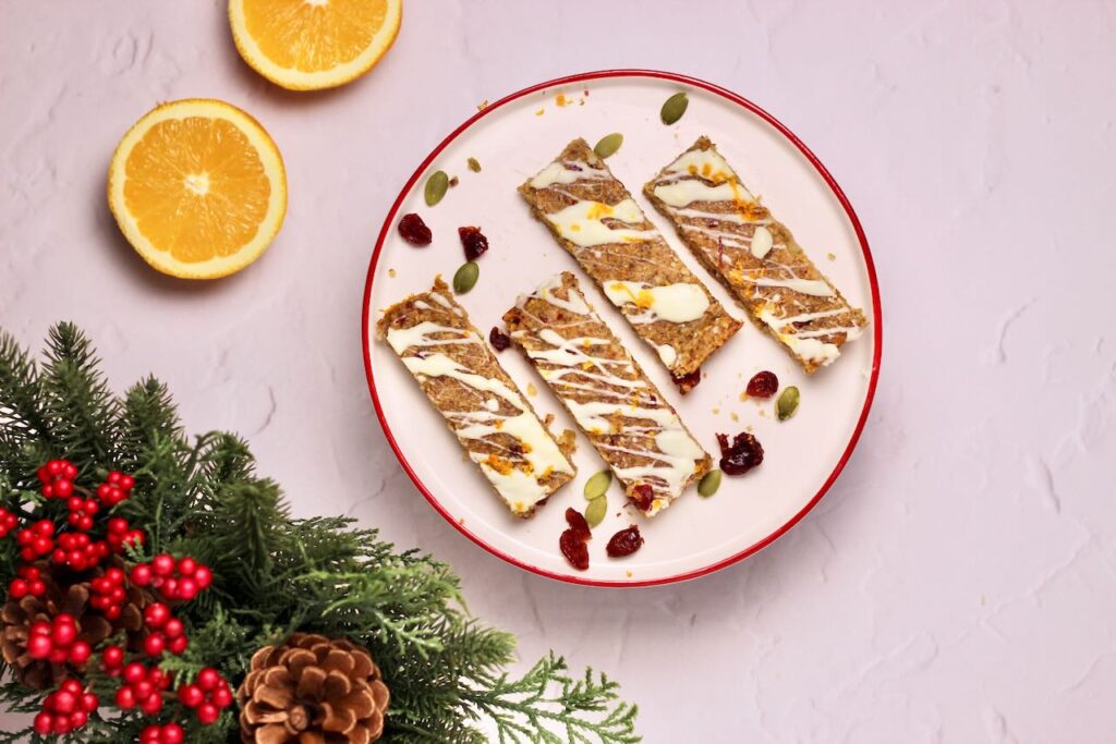 Cranberry Orange Energy Bars on plate with sliced oranges and decorative pine branch