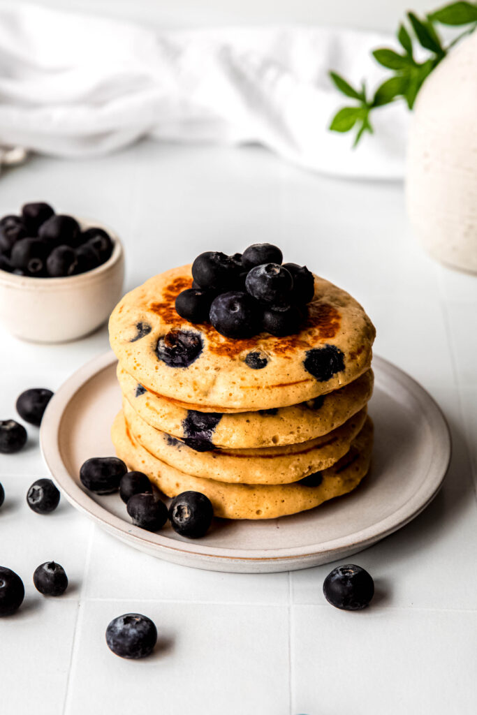 Four protein pancakes stacked topped with blueberries
